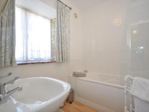 a white bathroom with a tub and a sink at 1 Bed in Bourton-on-the-Water 44961 in Withington