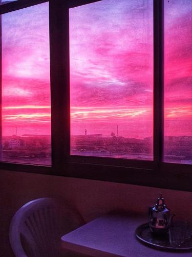 a room with two windows with a view of a sunset at Ifni Bay Residence - Sidi Ifni in Sidi Ifni