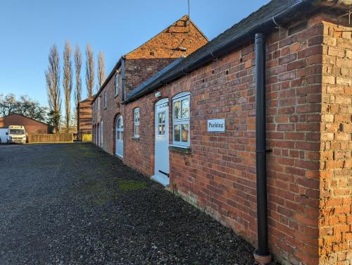 a brick building with a white door on a street at Wold Escapes, Highfield Farm in Great Driffield