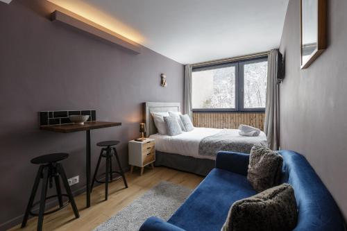 1 dormitorio con 1 cama y 1 sofá azul en Beautiful mountain view studio by the lake, en Chamonix-Mont-Blanc