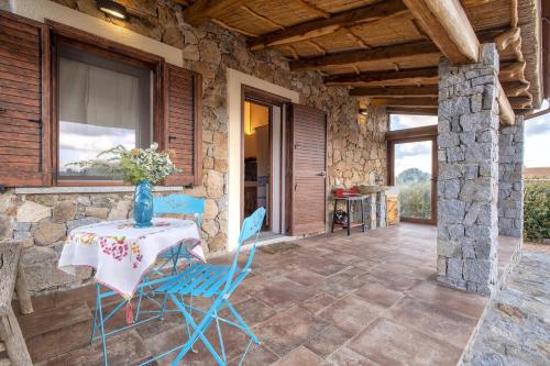 a stone house with a table and chairs on a patio at Stazzo Jana in Trinità dʼAgultu