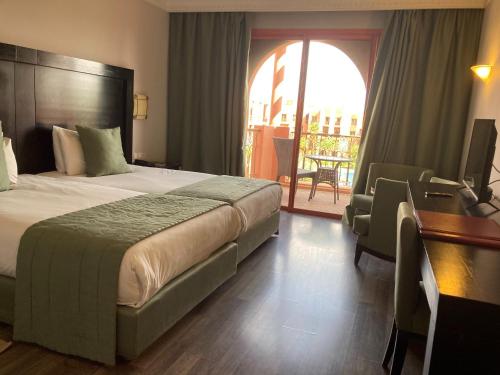 a hotel room with a bed and a desk and a balcony at Palm Plaza Marrakech in Marrakech