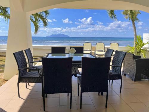 a dining room with a table and chairs and the beach at Ocean View Villa - Beauvallon villas in Beau Vallon