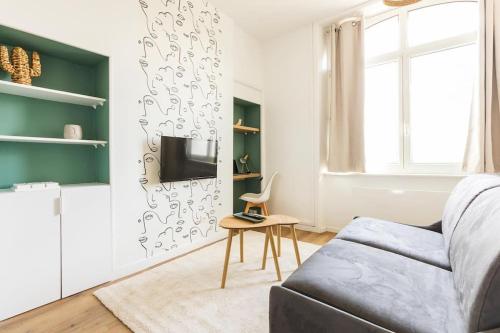 ein Wohnzimmer mit einem Sofa und einem TV in der Unterkunft Studio escale élégante - proche gare Saint-Brieuc in Saint-Brieuc