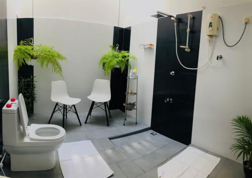 ein Bad mit einem WC, 2 Stühlen und einer Dusche in der Unterkunft West Dene in Negombo