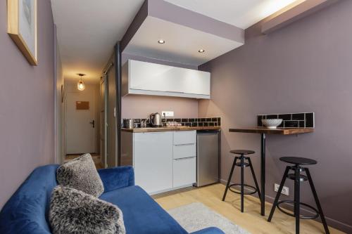 un salon avec un canapé bleu et une cuisine dans l'établissement Beautiful mountain view studio by the lake, à Chamonix-Mont-Blanc