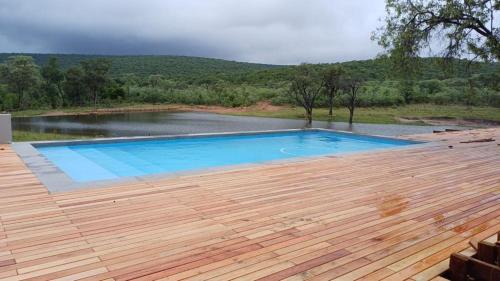 a swimming pool on a wooden deck with a lake at Ilanga Safari Lodge - Welgevonden Game Reserve in Vaalwater