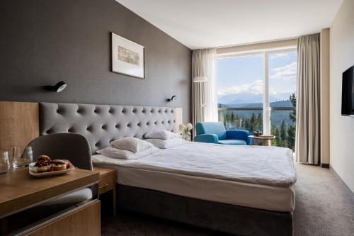 a hotel room with a bed and a large window at Hotel HARNAŚ dla dorosłych z widokiem na Tatry in Bukowina Tatrzańska