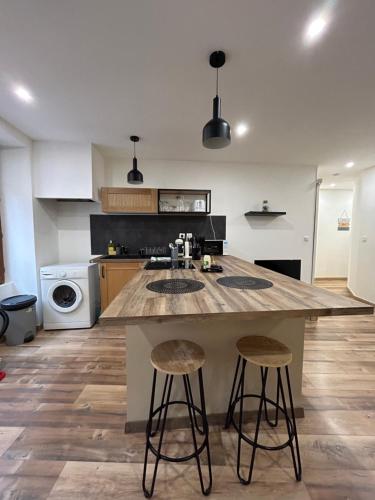 a kitchen with a large kitchen island with two bar stools at Appartement chaleureux en hyper centre de Gap in Gap