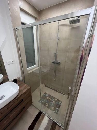 a bathroom with a glass shower with a sink at New spacious one-room apartment in Prievoz