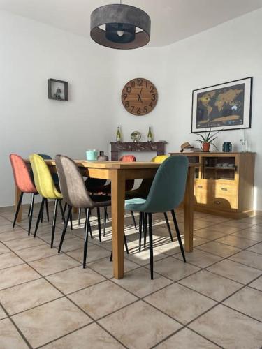 une table à manger avec des chaises et une horloge murale dans l'établissement Maison 2 chambres tout équipée, à Vitry-en-Artois