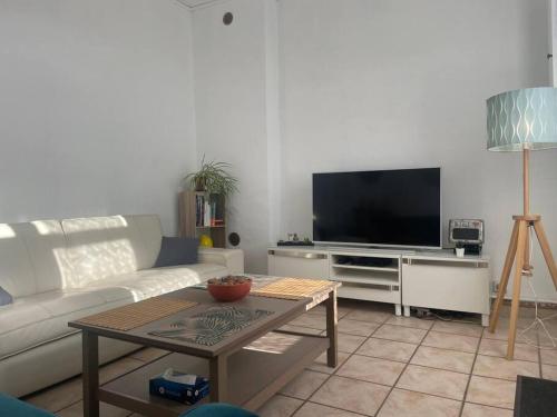 a living room with a white couch and a tv at Maison 2 chambres tout équipée in Vitry-en-Artois