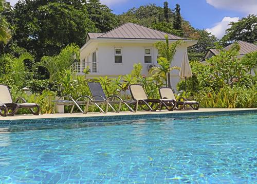 a swimming pool with chairs and a house at Villa Blanc in Beau Vallon