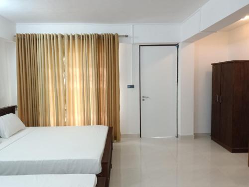 a bedroom with two beds and a sliding glass door at Spice Village Hotel & Restaurant in Habarana