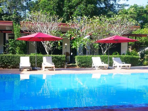 a pool with two chairs and two umbrellas at Big Elk Steak House - HomeStay in Trat