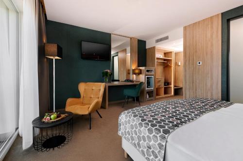 a bedroom with a bed and a desk with a chair at Hotel Ózon & Luxury Villas in Mátraháza