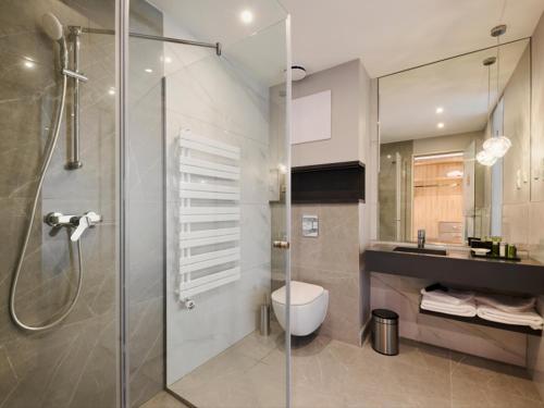 a bathroom with a shower and a toilet and a sink at Hotel Ózon & Luxury Villas in Mátraháza