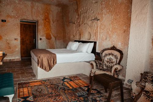 um quarto com uma cama e uma cadeira num quarto em MASAL CAVE SUITES OTEL em Ürgüp