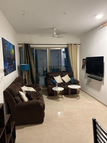 Room in Flat with Amazing City and Sea View في مومباي: غرفة معيشة مع كنب وتلفزيون بشاشة مسطحة