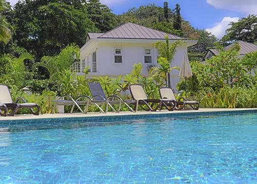 a pool with chairs and a house in the background at Les Jolies Eaux Villa - Chateau Elysium in Beau Vallon
