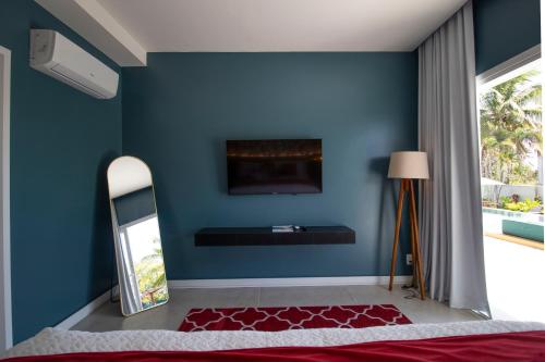 a bedroom with a blue wall and a mirror at The View - Adults Only Resort in Pipa