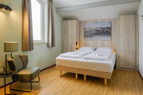 1 dormitorio con 1 cama y 1 silla en Summio Vakantiepark Reevallis, en Vijlen