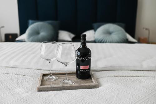 a bottle of wine and two wine glasses on a bed at Studio apartman Aurora in Đakovo