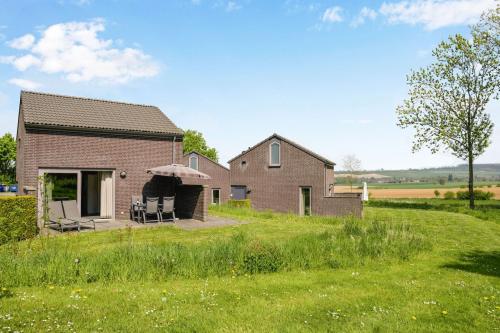 a brick house with chairs and an umbrella at Summio Vakantiepark Reevallis in Vijlen