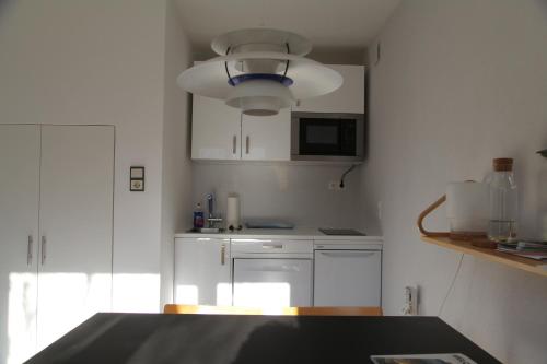 a kitchen with white cabinets and a blue light fixture at Gartenstudio Peony in Innsbruck