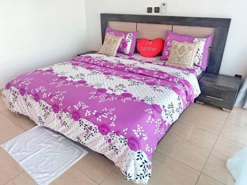 a purple bed with pink and white sheets and pillows at Les merveilles d’assinie in Assinie