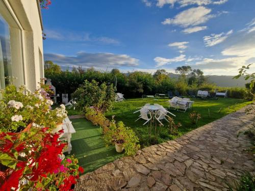 a house with a garden with flowers and a table at Pensiunea Poezii Alese in Valea Drăganului