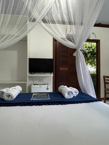 a bedroom with a bed with two towels at Casa Jasmim Imbassaí-BA in Mata de Sao Joao