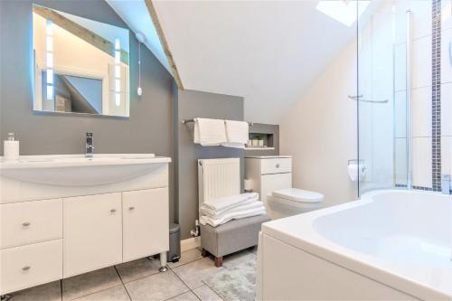 a white bathroom with a sink and a toilet at The Crossing Cottage in Pwllheli