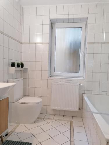 a white bathroom with a toilet and a window at Stilvolle Wohnung an der Alten Mainbrücke in Würzburg