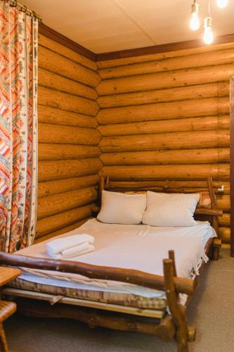a bed in a room with a wooden wall at Kolyba Opryshkiv in Nizhneye Selishche