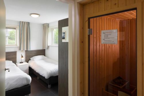 een kamer met 2 bedden en een deur naar een slaapkamer bij Summio Waterpark Zwartkruis in Noordbergum