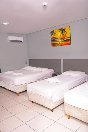 a room with three beds and a painting on the wall at Hotel Aquarius in Fortaleza