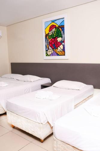 three beds in a room with a painting on the wall at Hotel Aquarius in Fortaleza