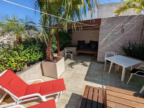 a patio with red chairs and a table and a palm tree at Cobertura Duplex/Penthouse em Copacabana in Rio de Janeiro