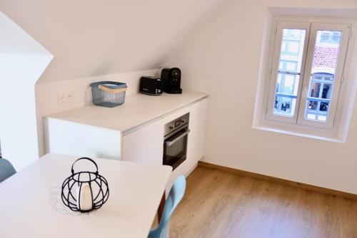 uma cozinha branca com uma mesa e uma janela em Margarita Apt Climatisé T2 4 pers Centre parking em Le Touquet-Paris-Plage