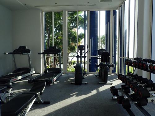 un gimnasio con una gran ventana y filas de máquinas de ejercicio en Chelona Hua Hin, en Khao Tao