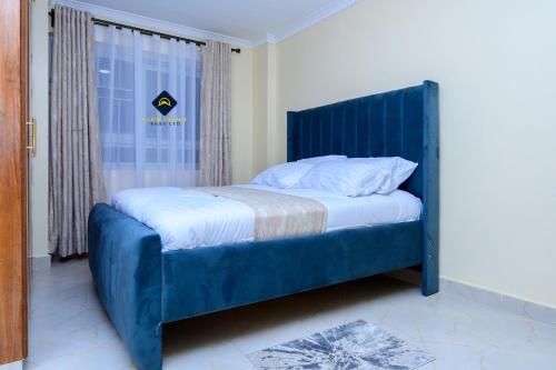 łóżko z niebieskim zagłówkiem w pokoju w obiekcie Jalde Heights, Limuru Road, 178, Nairobi City, Nairobi, Kenya w mieście Nairobi