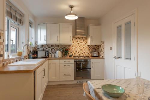 a kitchen with white cabinets and a table with a plate on it at 17 St Edmunds Road in Southwold