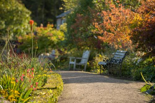 a park with two benches and flowers in a garden at Off Grid Travel at Cambo Estate in St. Andrews