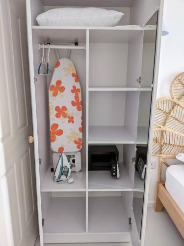 a white book shelf with a surfboard on it at Seaview serenity apartment in Flic-en-Flac