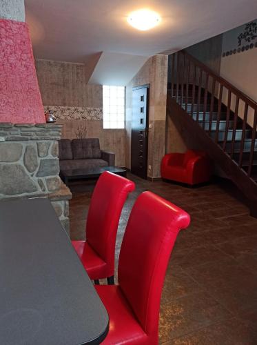 a living room with two red chairs and a table at Apartaments Gory in Niedzica Zamek