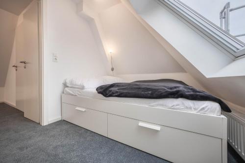 a white bedroom with a bed under the stairs at Appartment Malerviertel in Braunschweig