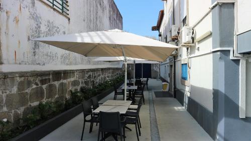 a table and chairs with an umbrella on a sidewalk at Hotel Senhor de Matosinhos in Matosinhos