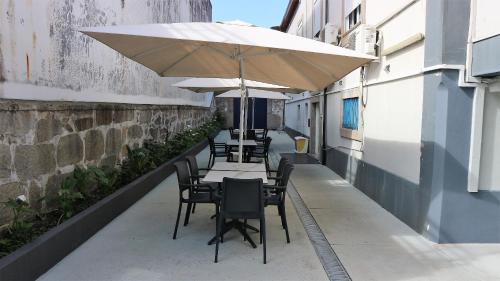 a row of tables and chairs with an umbrella at Hotel Senhor de Matosinhos in Matosinhos