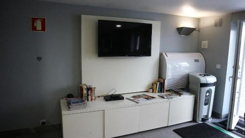 a room with a refrigerator and a television on a wall at Hotel Senhor de Matosinhos in Matosinhos